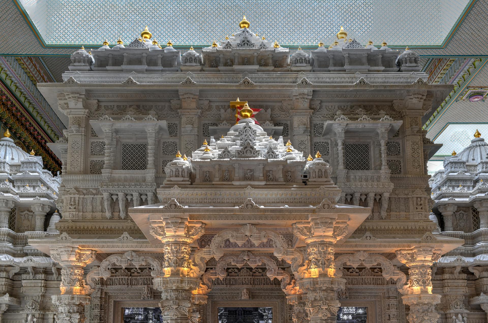 An ornate white-marble temple interior with carved detail and gilded domes.